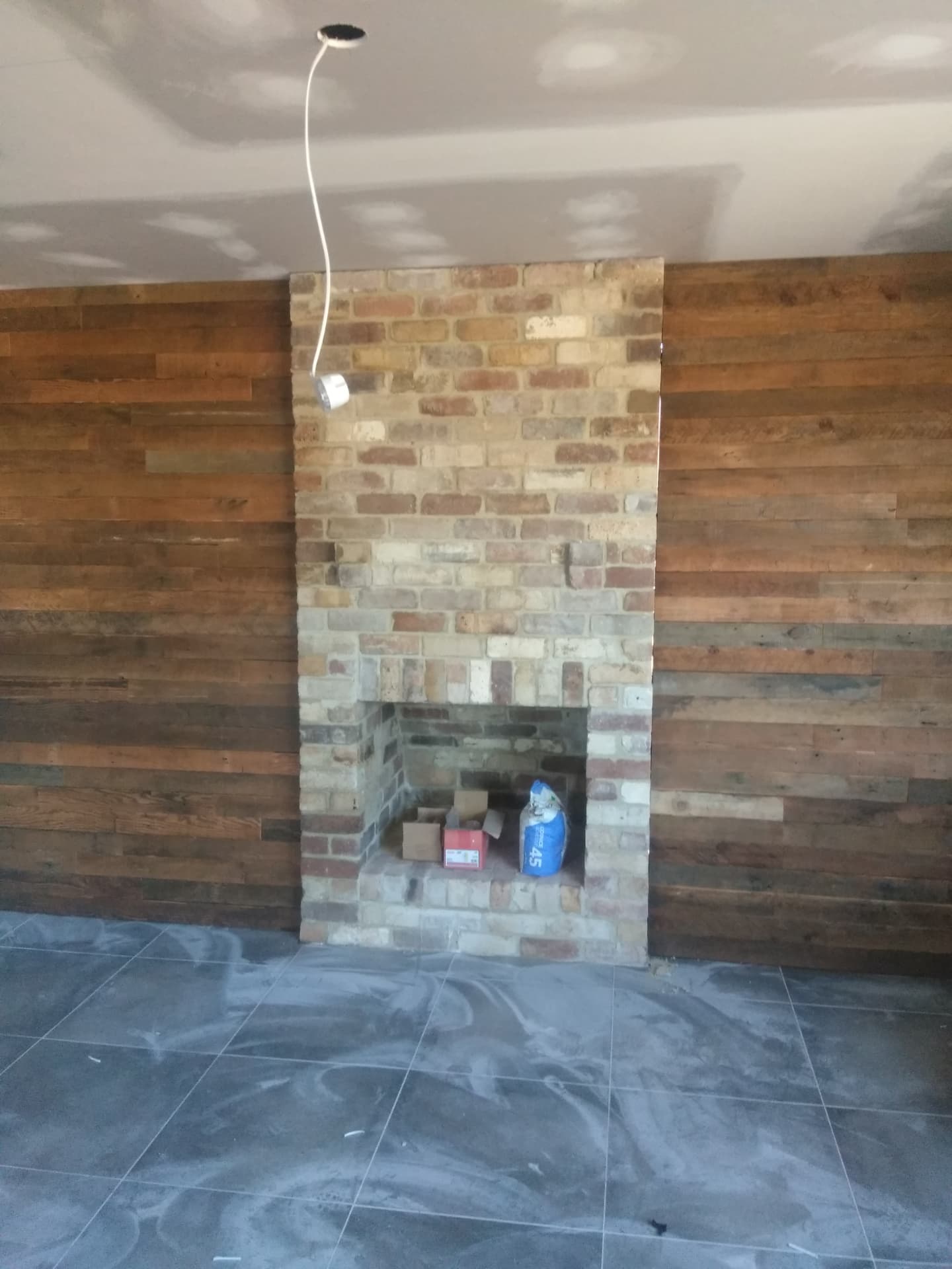 Indoor recycled brick fireplace against a timber lined feature wall