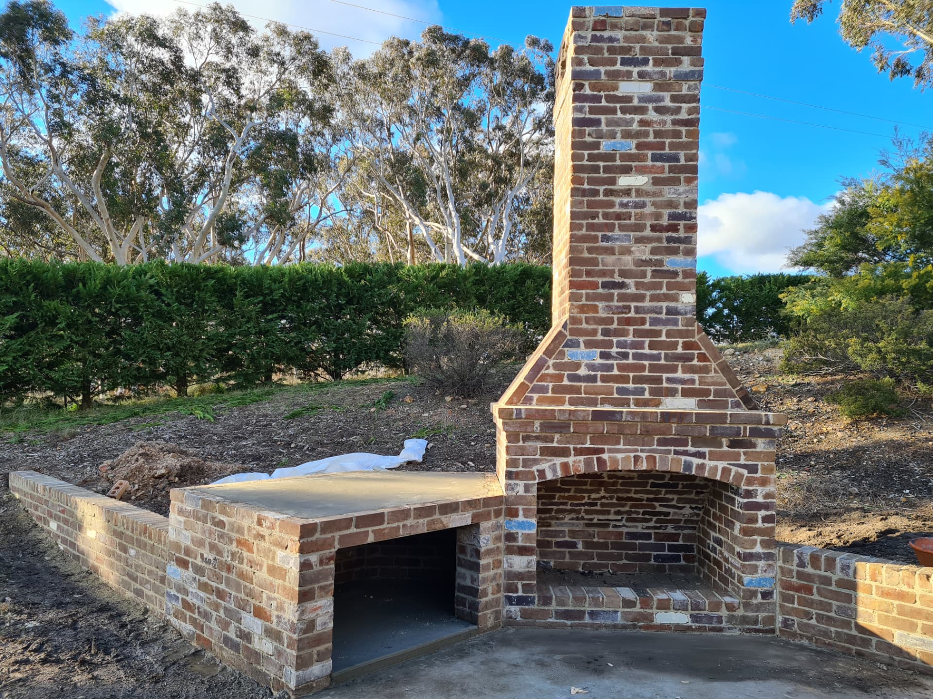 Outdoor recycled brick fireplace and chimney with bench in a Hunter Valley backyard