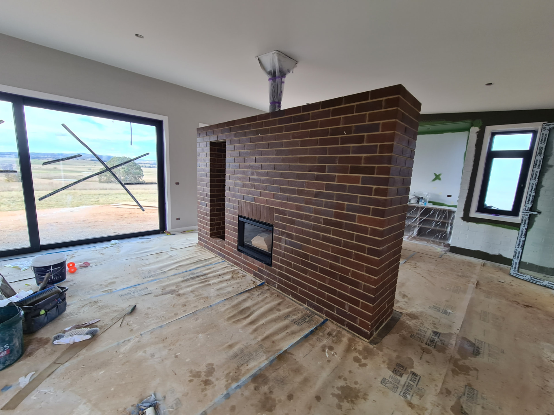 Internal dark face brick fireplace feature wall with an inbuilt fire
