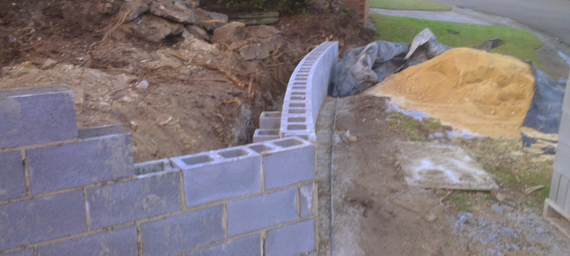 Curved core filled block retaining wall under construction on a sloping block